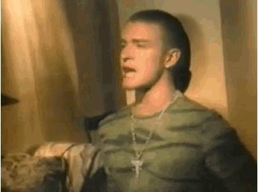 a man wearing a camouflage shirt and a cross necklace is singing .
