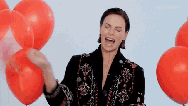 a woman is surrounded by red balloons and says marie claire in the corner