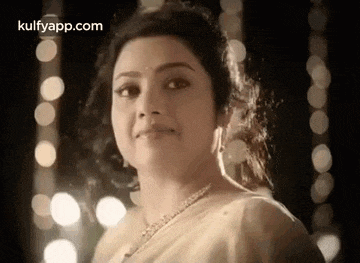 a close up of a woman wearing a necklace and a white saree .