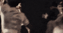 a blurry photo of a group of people dancing in a dark room .
