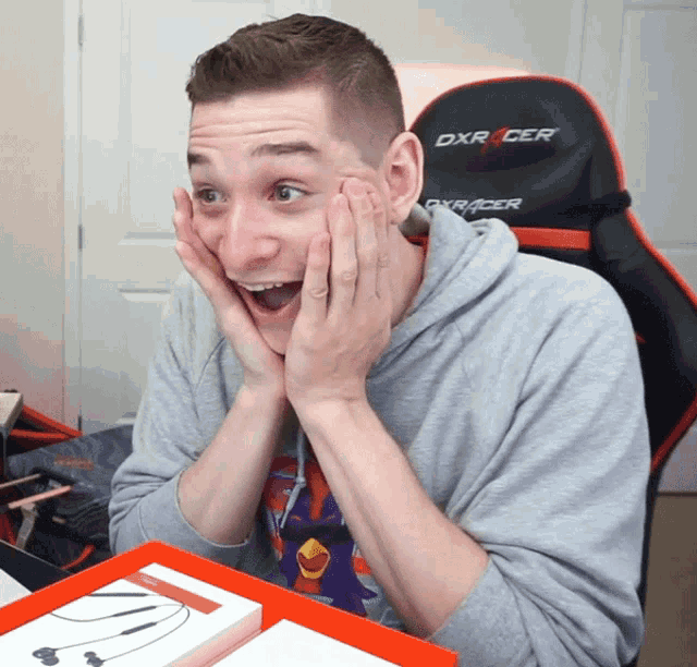 a man sitting in a dxracer chair holds his hands to his face