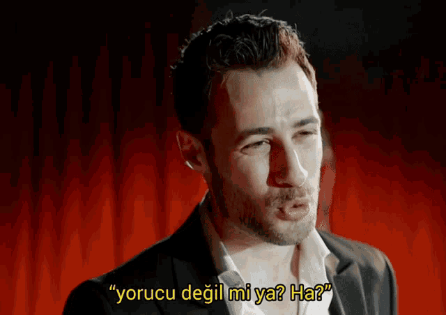 a man in a suit and tie says " yorucu degil mi ya ? ha "