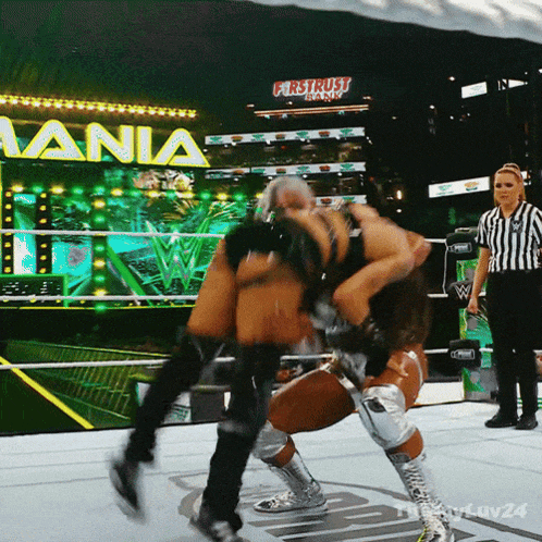 a wrestling match takes place in front of a sign that says " first trust bank "