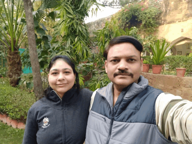 a man and a woman pose for a selfie in front of trees