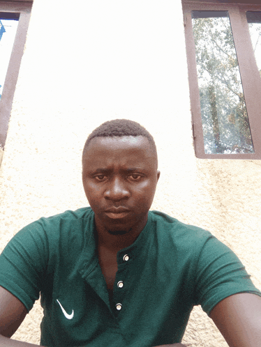 a man in a green nike shirt is looking at the camera