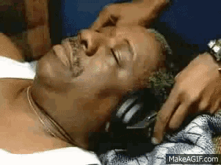 a man is laying on a bed with his eyes closed and a person is touching his face .