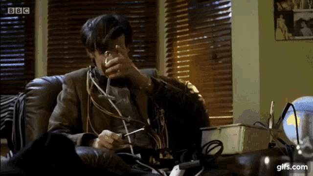 a man is sitting on a couch holding a glass of wine and a pair of scissors .