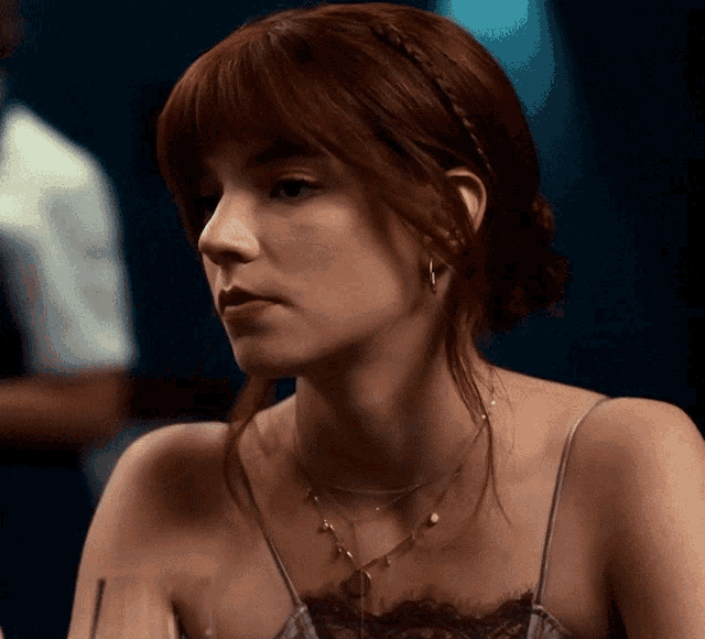 a woman with red hair wearing a braided headband and a necklace