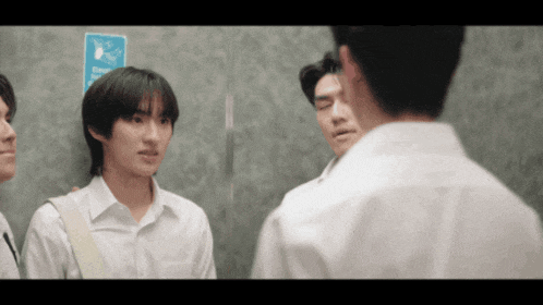 a group of young men are standing next to each other in an elevator talking to each other