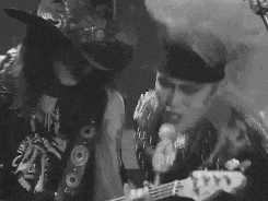 a man and a woman are singing into microphones while playing guitars .