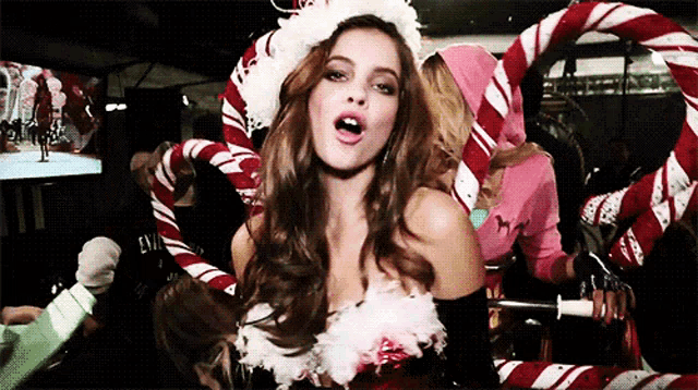 a woman in a santa costume with candy canes around her