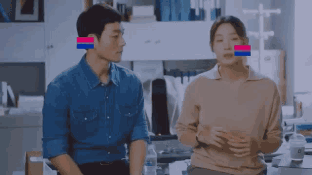 a man and a woman are sitting next to each other in an office with a bisexual flag on their ears .