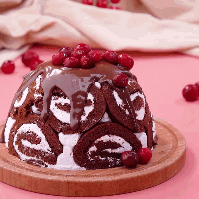 a chocolate cake on a wooden cutting board with cranberries on top
