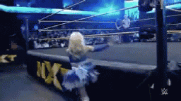 a woman in a blue dress is dancing in a wrestling ring