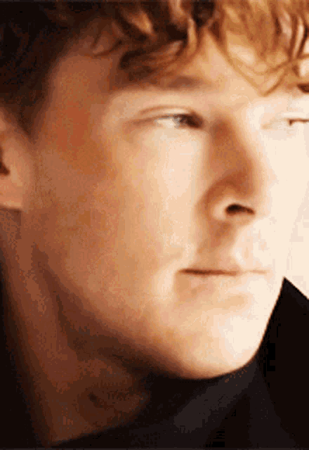 a close up of a man 's face with a black shirt