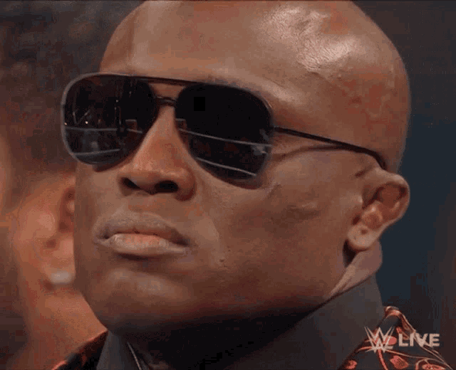 a close up of a man wearing sunglasses with a w live logo in the corner