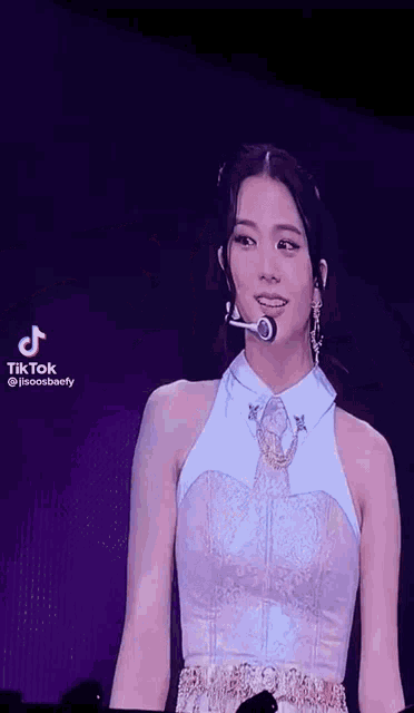 a woman in a white dress is standing on a stage with a microphone in her hand .
