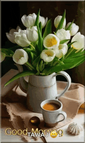 a vase of white tulips next to a cup of coffee .