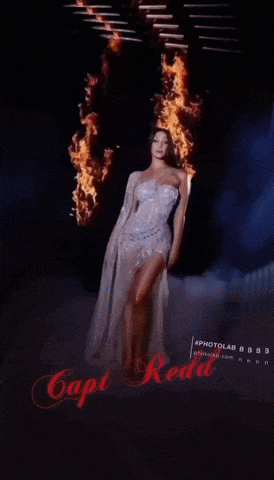 a woman in a white dress is standing in front of a fire and smoke with the caption capt red