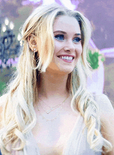 a woman with blonde hair and blue eyes is smiling and wearing a white dress