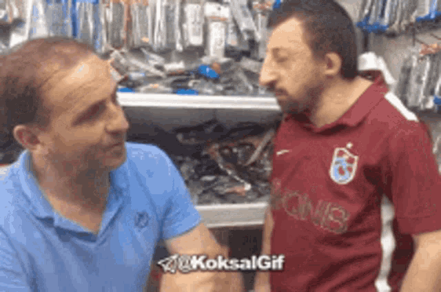 two men are talking in a store and one has a shirt that says qnb on it
