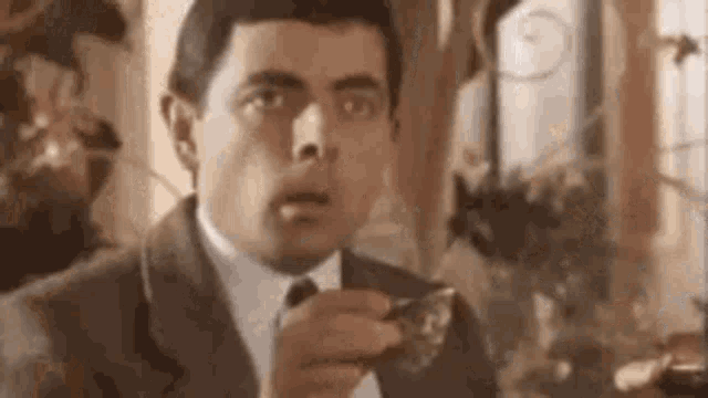 a man in a suit and tie is eating a piece of food with a spoon .