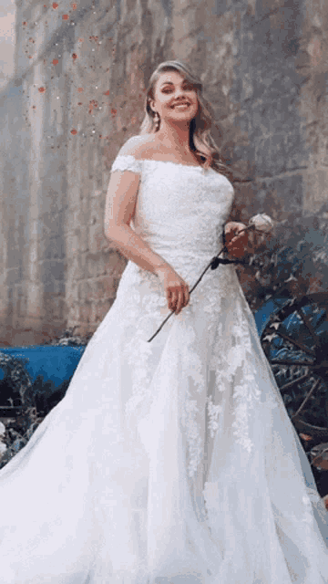 a woman in a white wedding dress holds a rose