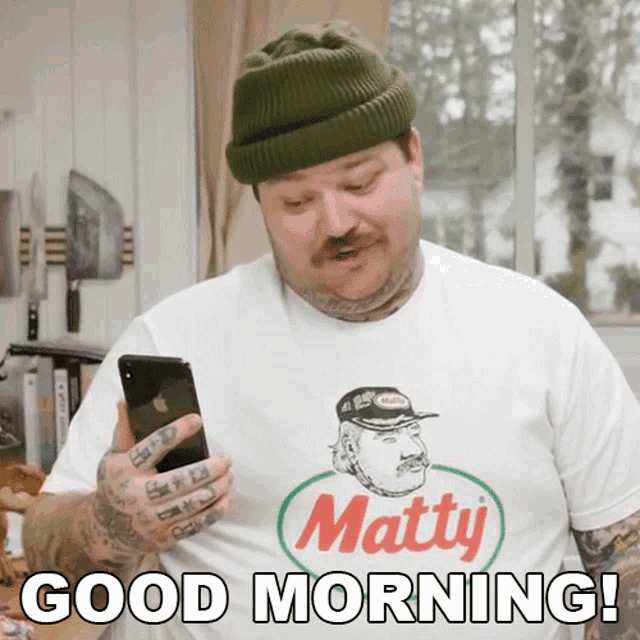 a man wearing a shirt that says matty holds a cell phone
