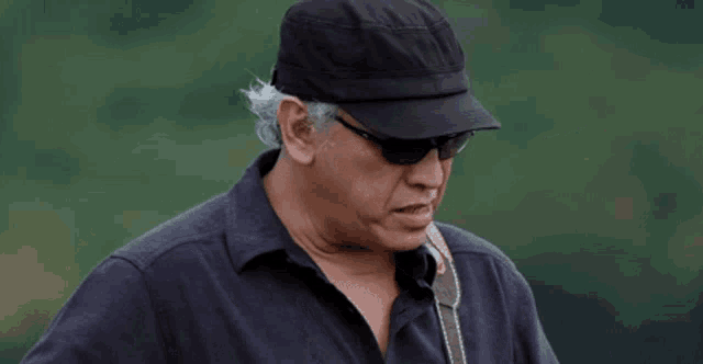 a man wearing sunglasses and a hat looks down