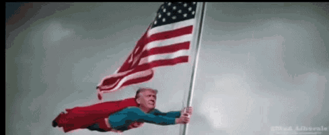a man dressed as superman is flying through the air while holding an american flag .