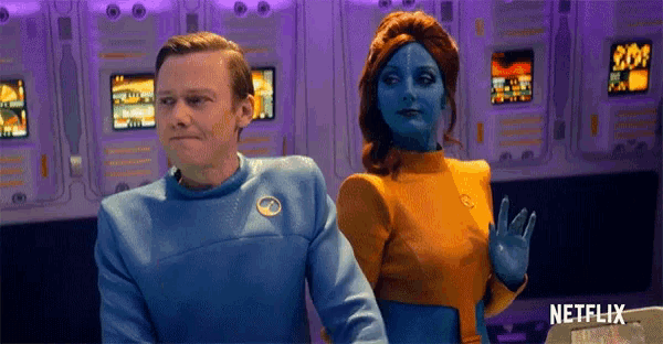 a man and a woman are standing next to each other in a room . the woman is blue and the man is orange .