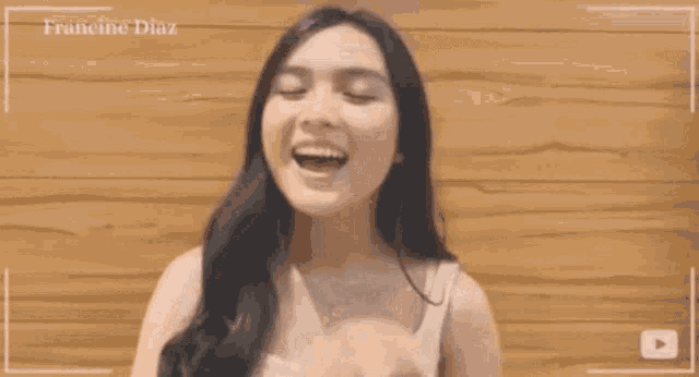 a woman making a heart shape with her hands in front of a wooden wall