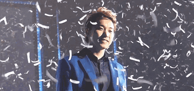 a man in a blue jacket is standing in front of a wall of confetti