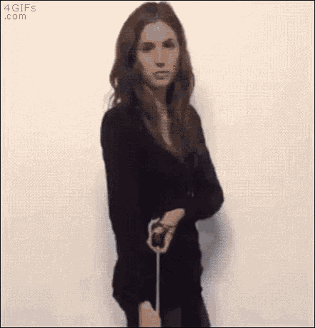 a woman in a black dress is holding a rope in her hand .
