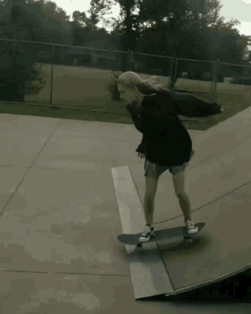 a girl rides a skateboard down a ramp at a skate park
