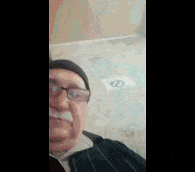 a man wearing glasses and a hat is making a funny face while sitting on the floor .