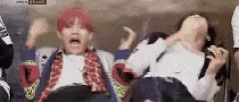 a group of people are sitting on a chair with their mouths open and their hands in the air .