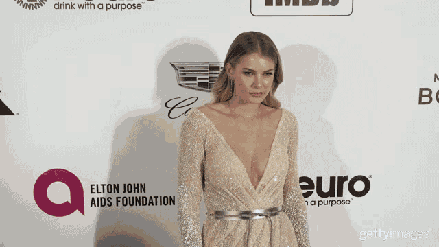 a woman in a dress is standing in front of an elton john aids foundation logo