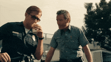 two police officers are standing next to each other one is drinking from a cup