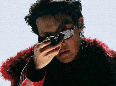 a man wearing a red fur coat is holding a camera
