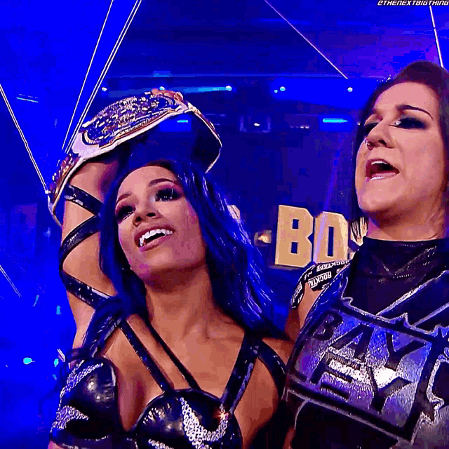 two female wrestlers are posing for a photo in front of a sign that says ' bb '