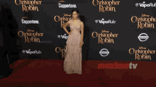 a woman in a dress stands on a red carpet that says disney christopher robin on it