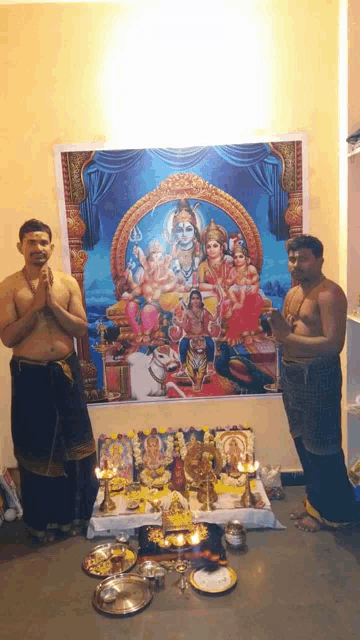 two men are praying in front of a painting of shiva