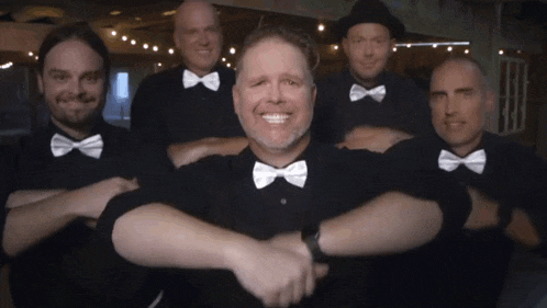 a group of men wearing bow ties pose for a photo