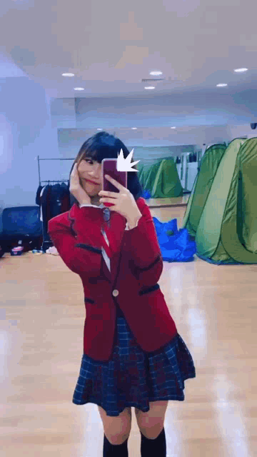 a girl in a school uniform is taking a picture of herself in the mirror