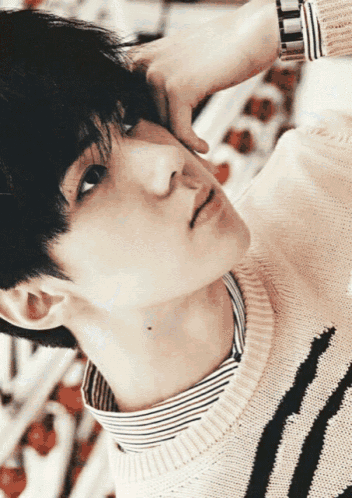 a close up of a person 's face with a striped shirt and sweater