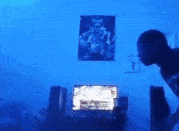 a man is standing in front of a computer monitor with a blue light behind it