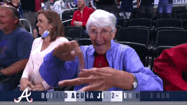 an older woman sitting in a stadium watching ronald acua jr. 2 unh run