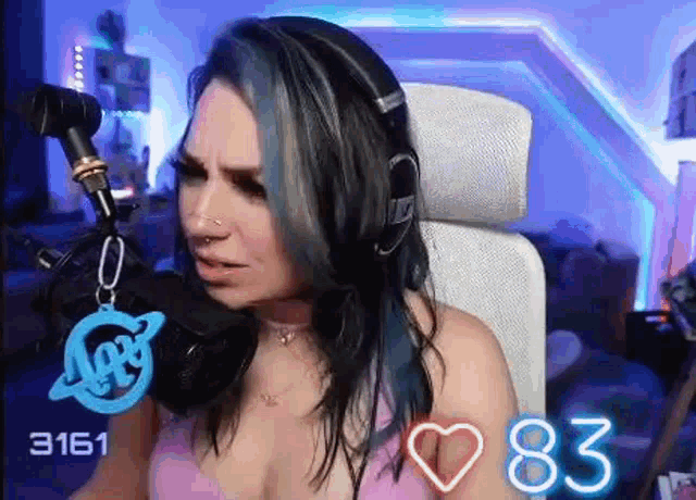 a woman with blue hair and headphones is sitting in front of a microphone in a chair .