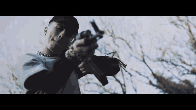 a man in a hat is holding a gun in his right hand